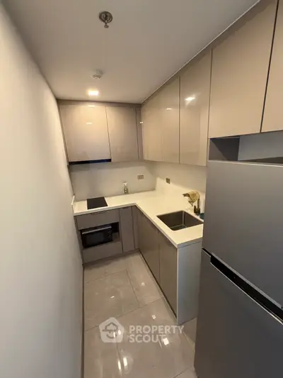 Modern compact kitchen with sleek cabinetry and built-in appliances in a stylish apartment.