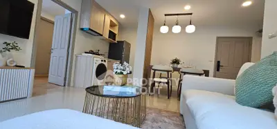 Modern open-plan living room with cozy seating and stylish dining area, featuring contemporary decor and appliances.