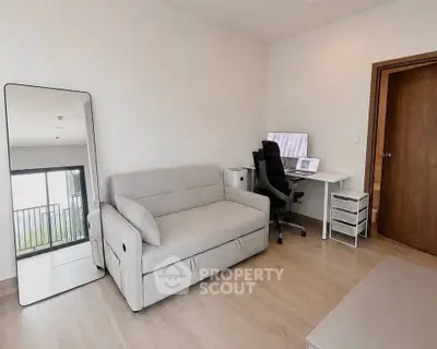 Modern study room with sleek desk, ergonomic chair, and cozy sofa in a bright apartment.