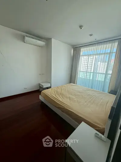 Spacious bedroom with large window and air conditioning in modern apartment