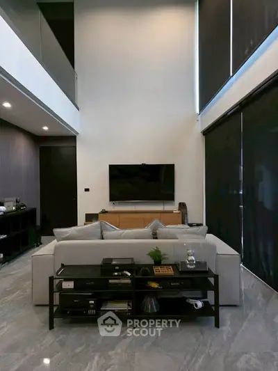 Luxurious modern living room with high ceilings and sleek design, featuring a stylish sofa and entertainment setup.