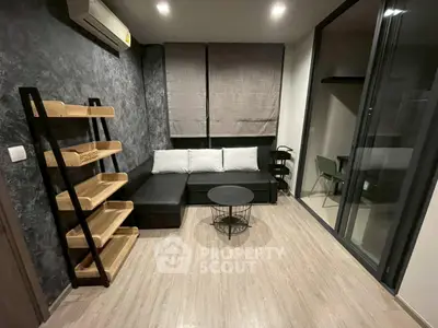 Modern living room with sleek black sofa, wooden shelves, and stylish decor in a cozy apartment.
