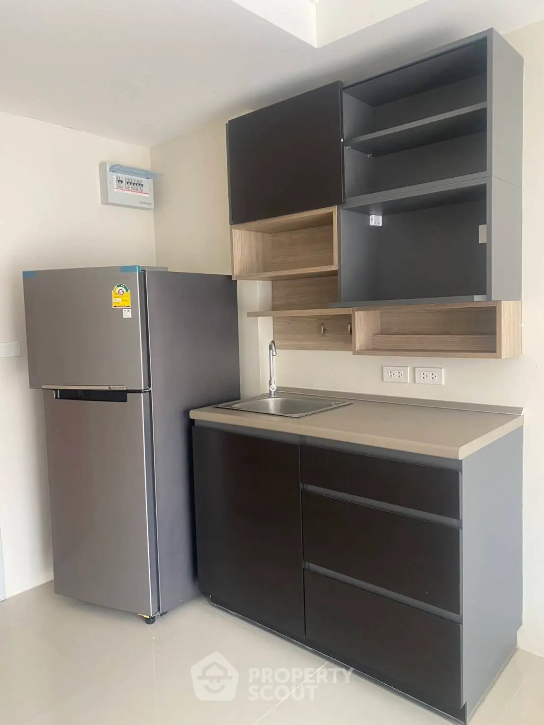 Modern kitchen with sleek cabinets and stainless steel fridge in a compact layout.
