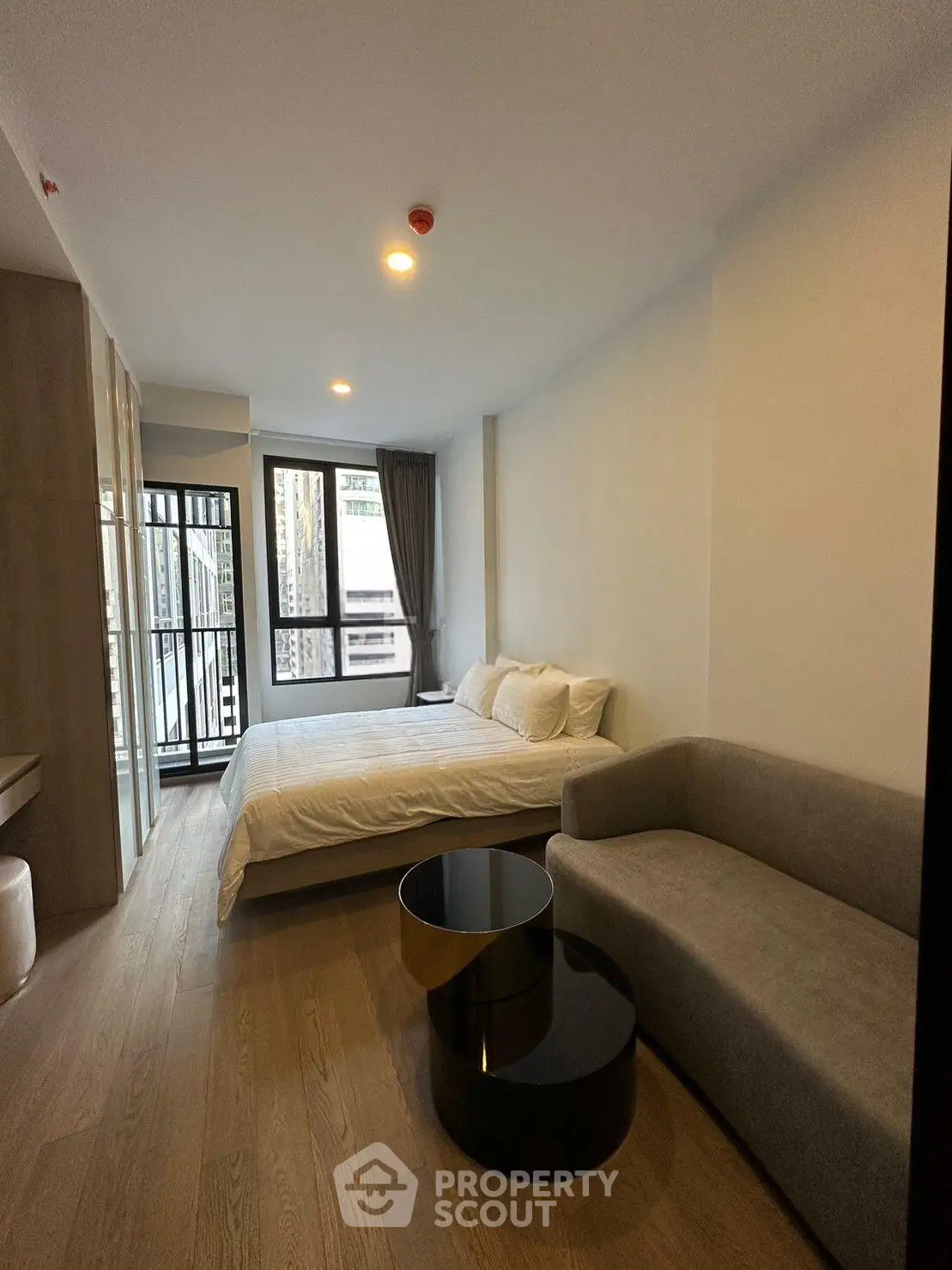 Modern bedroom with cozy bed, stylish sofa, and large window for natural light.