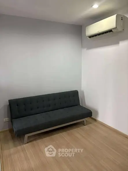 Modern minimalist living room with sleek sofa and air conditioning unit.