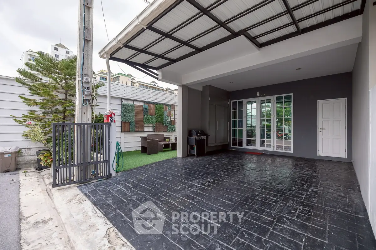 Spacious covered carport with modern design and outdoor seating area in a residential property.