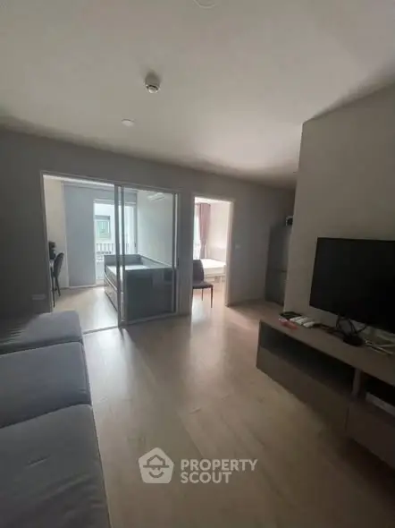 Modern living room with sleek furniture and open layout, featuring a TV and natural light.