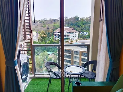 Charming balcony with lush view and cozy seating area in modern apartment.