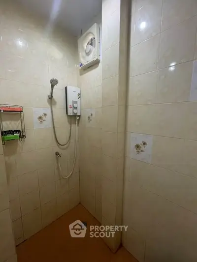 Compact bathroom with shower and water heater, ideal for efficient space use.