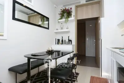 Modern dining area with sleek black table and chairs, minimalist decor, and open kitchen layout.