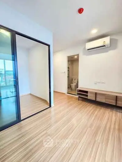 Modern apartment interior with wooden flooring, glass partition, and air conditioning unit.