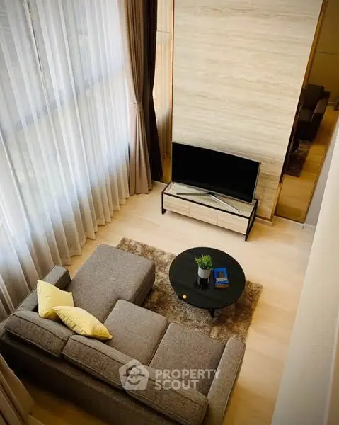 Modern living room with high ceilings, large windows, and cozy seating area.