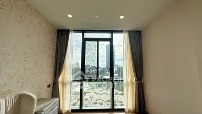 Spacious room with large window offering stunning city view and elegant decor.
