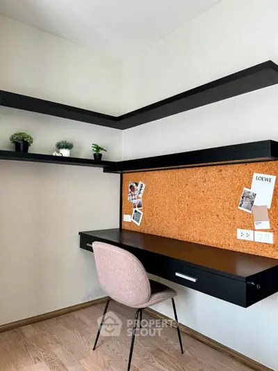 Modern study nook with sleek black desk, corkboard, and floating shelves in a stylish home office.