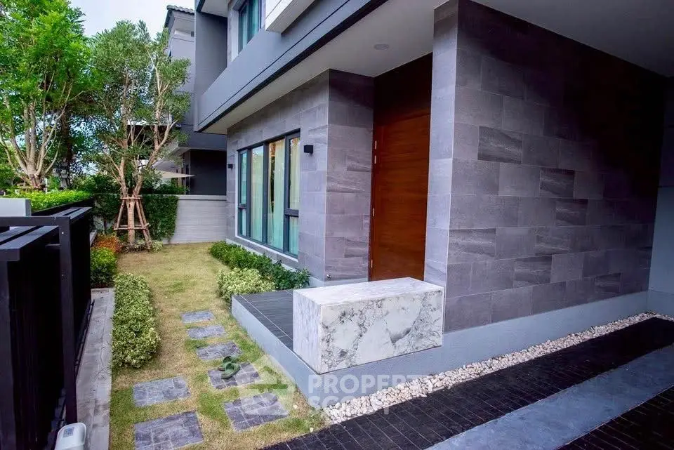 Modern house exterior with sleek stone facade and landscaped garden