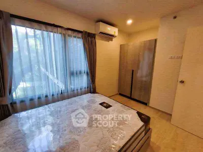 Cozy bedroom with large window and modern furnishings, perfect for relaxation and comfort.