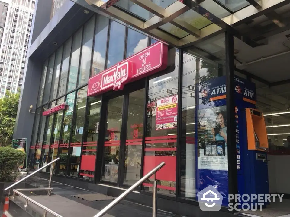 Modern commercial building entrance with glass facade and ATM machines.