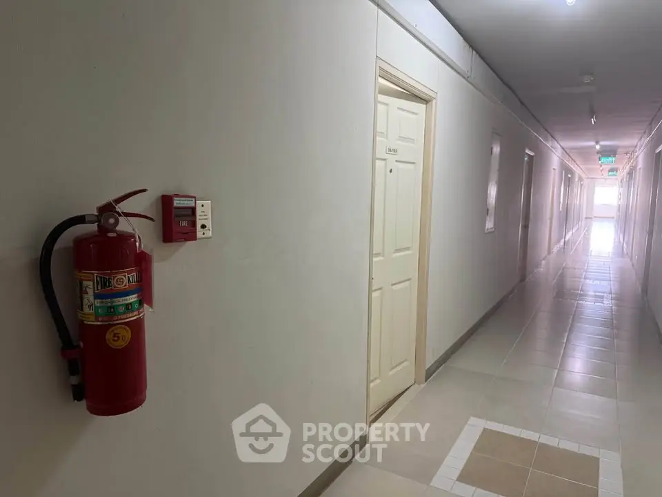 Spacious apartment corridor with fire safety equipment and tiled flooring.