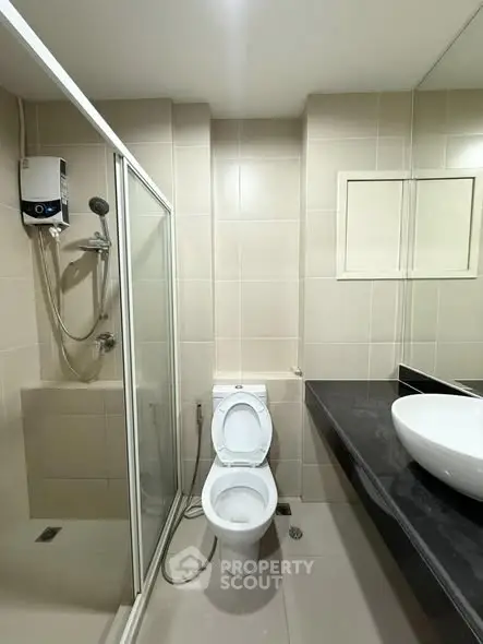 Modern bathroom with shower, toilet, and sleek countertop basin.