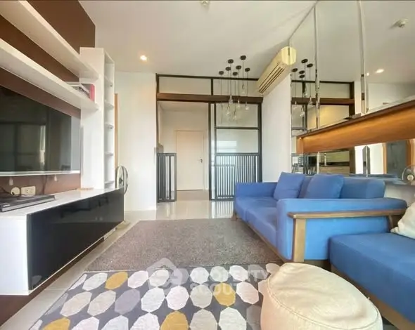 Modern living room with blue sofa, stylish decor, and large TV unit