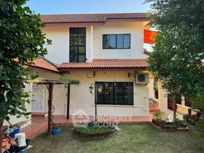 Charming two-story house with red-tiled roof and lush garden, perfect for family living.