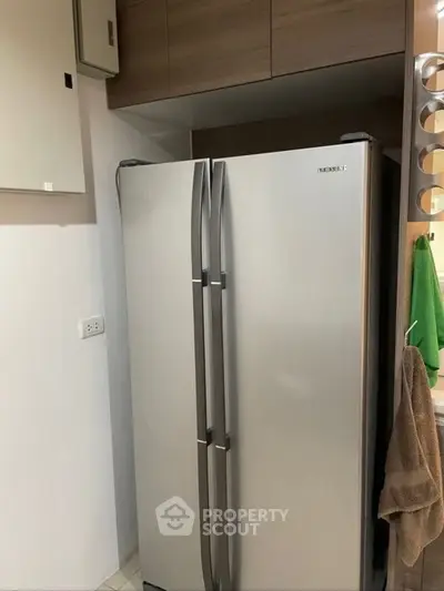 Modern kitchen with sleek stainless steel refrigerator and wooden cabinets.