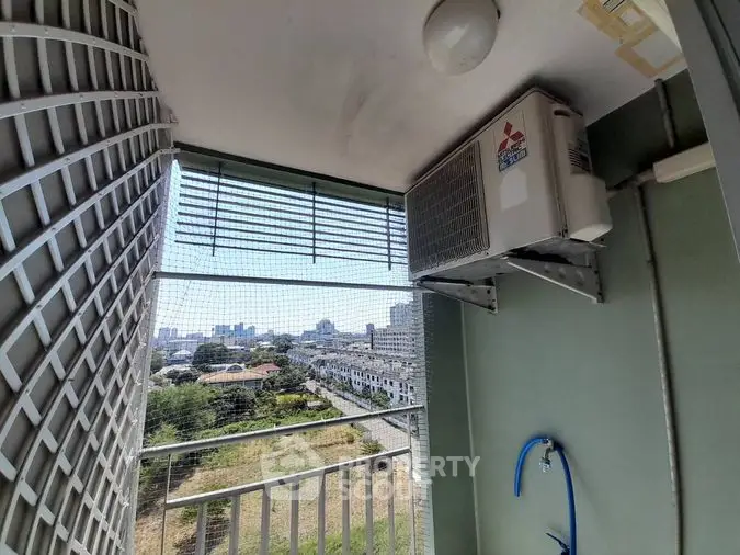 Compact balcony space with urban view, featuring safety grills and an air conditioning unit, ideal for high-rise city living.