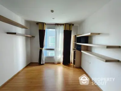 Spacious modern living room with wooden flooring and large window view.