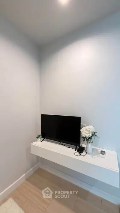 Modern minimalist living room corner with mounted TV and floral decor