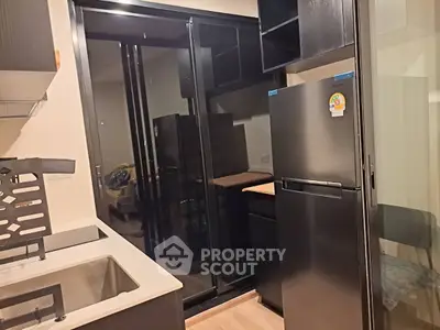 Modern kitchen with sleek black appliances and glass door leading to balcony.