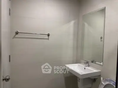 Modern bathroom with sleek sink and large mirror in a minimalist design.
