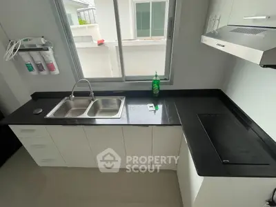 Modern kitchen with sleek black countertops and stainless steel appliances.