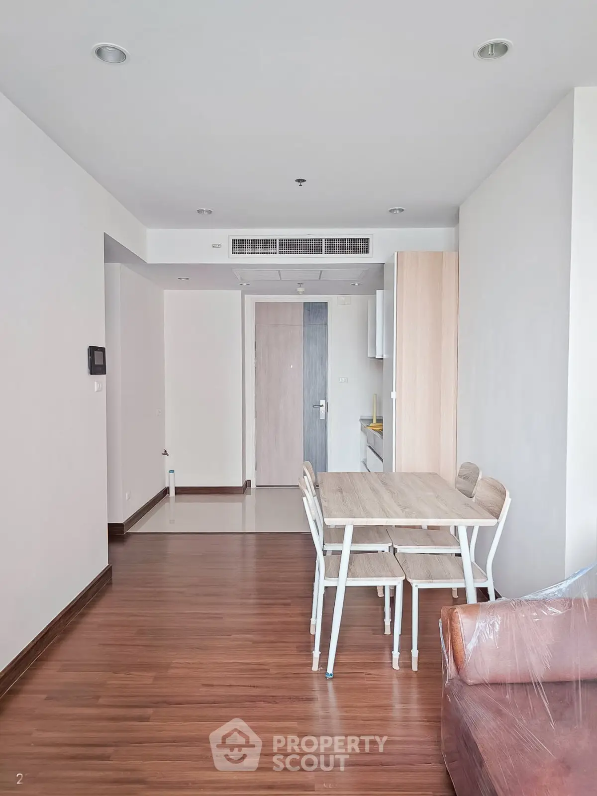 Modern apartment interior with wooden flooring and dining area, showcasing minimalist design and natural light.