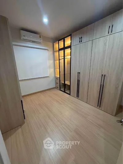 Spacious bedroom with modern built-in wardrobes and sleek wooden flooring.