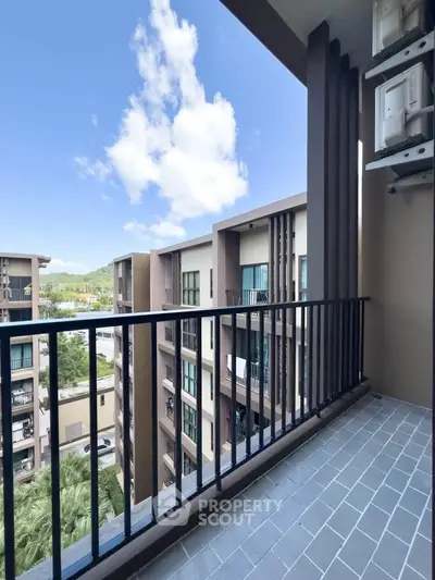 Spacious balcony with stunning view of modern apartment complex and clear blue sky.