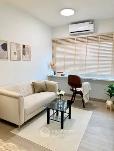 Modern living room with cozy sofa, stylish decor, and natural light from large window.