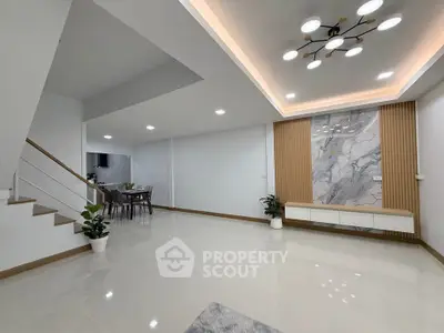 Spacious modern living room with elegant lighting and marble accent wall
