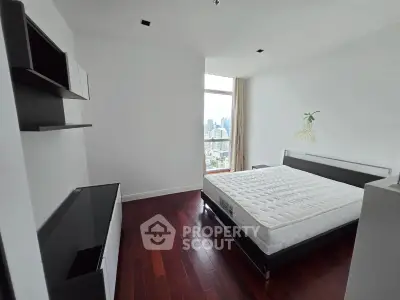 Spacious bedroom with city view and modern furnishings in high-rise apartment.