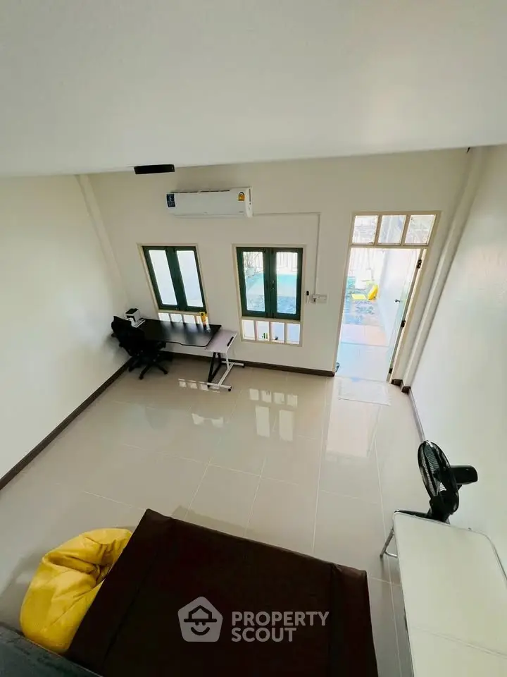 Modern living room with sleek design and natural light, featuring a workspace and cozy seating area.