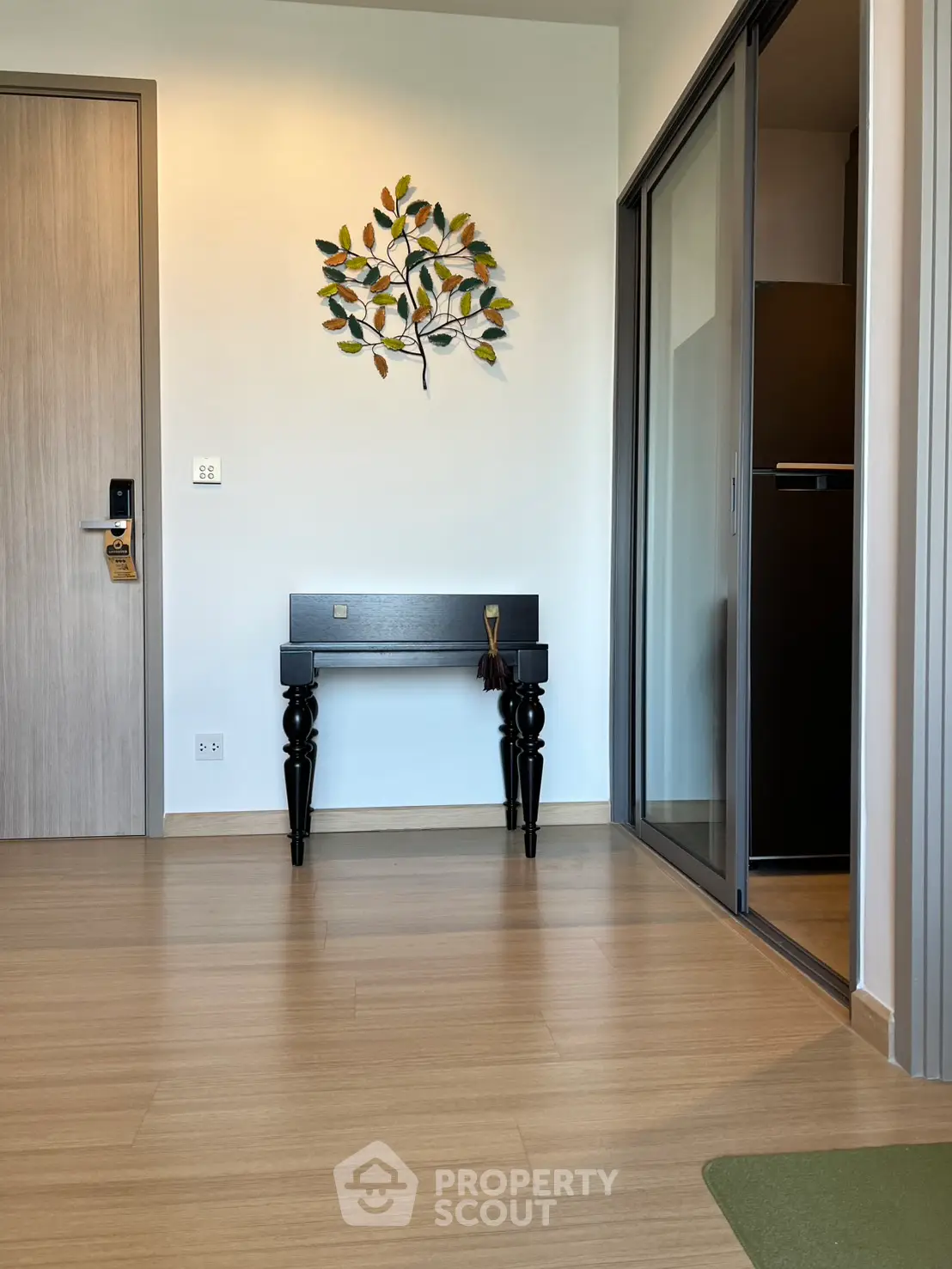 Modern interior with wooden flooring and stylish wall art, featuring a sleek black console table.