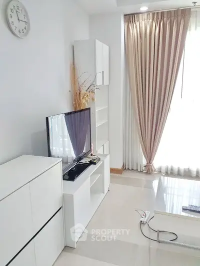 Modern living room with sleek white furniture and large window with elegant curtains.