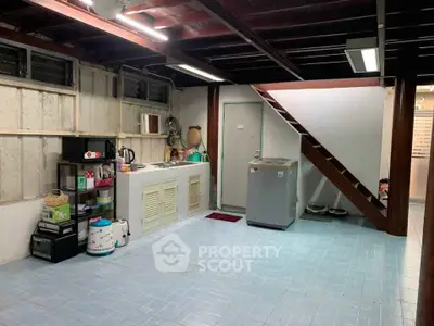 Spacious utility room with washing machine and storage under wooden staircase.