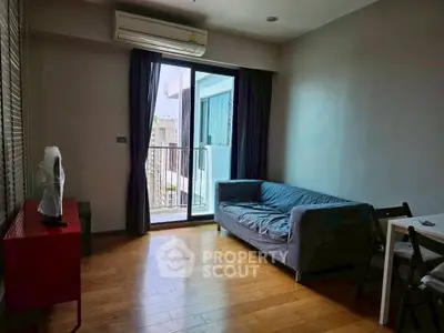 Cozy living room with wooden flooring, modern sofa, and balcony access in a stylish apartment.