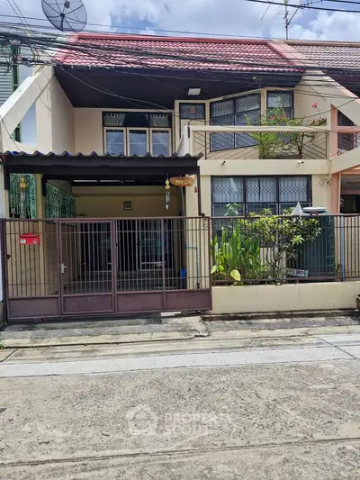 Charming two-story townhouse with gated entrance and lush greenery in a serene neighborhood.