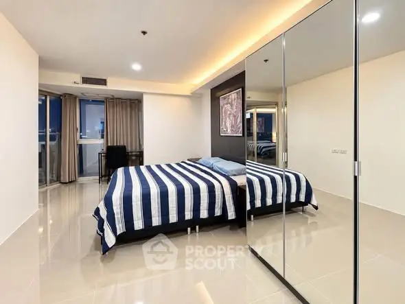 Spacious modern bedroom with mirrored wardrobe and stylish decor