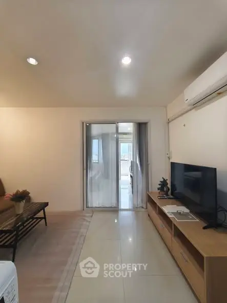 Modern living room with sleek TV unit and air conditioning, leading to a bright balcony with city views.