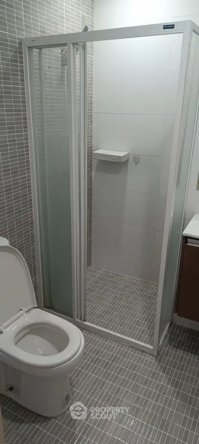 Modern bathroom with sleek shower enclosure and tiled flooring, perfect for contemporary living.