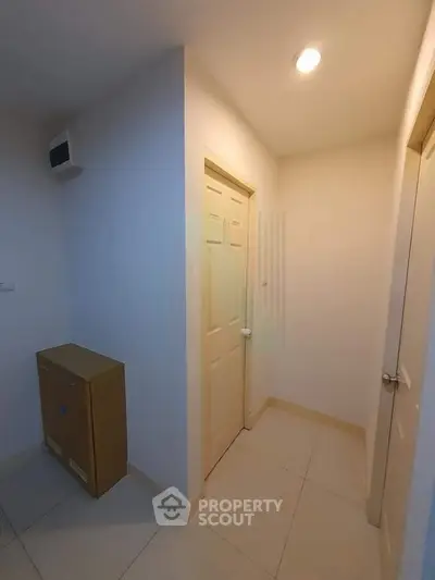 Minimalist hallway with closed doors and tiled flooring in modern apartment.