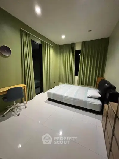 Spacious bedroom with modern decor and large windows for natural light.