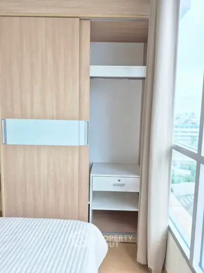 Modern bedroom with built-in wardrobe and large window offering natural light.